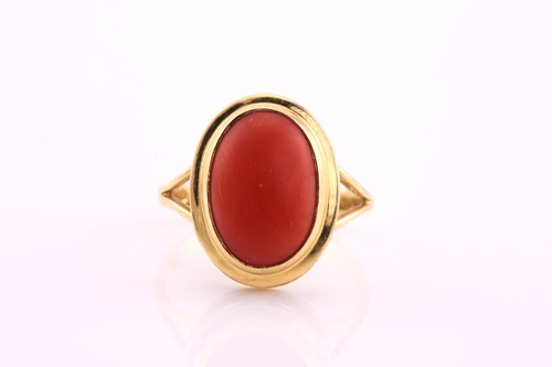 Lot 323 - A coral cabochon ring, the 13.2 x 9mm oval...