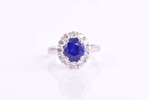 Lot 212 - A sapphire and diamond cluster ring, the oval...