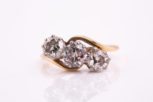 Lot 297 - A three stone diamond crossover ring; the...
