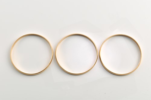 Lot 181 - Three solid closed bangles in yellow metal,...