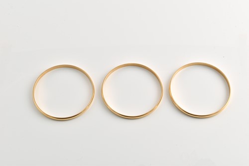 Lot 181 - Three solid closed bangles in yellow metal,...