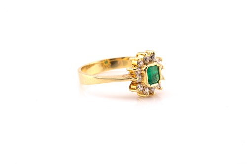Lot 149 - An emerald and diamond cluster ring, featuring...