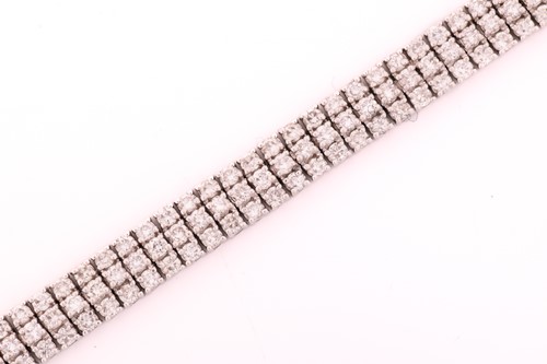 Lot 19 - A three-row diamond tennis bracelet, featuring...