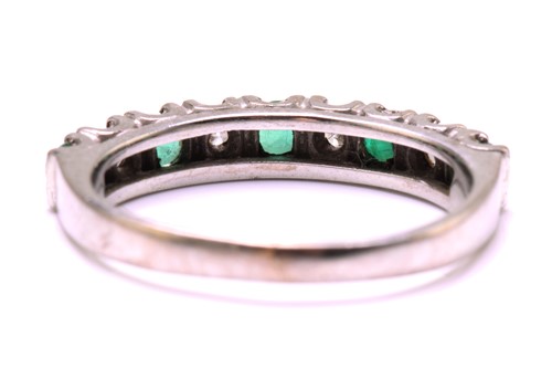 Lot 204 - An Emerald and diamond half eternity ring in...