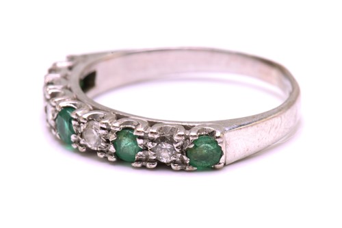 Lot 204 - An Emerald and diamond half eternity ring in...