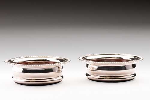 Lot 379 - A pair of silver wine coasters with gadrooned...