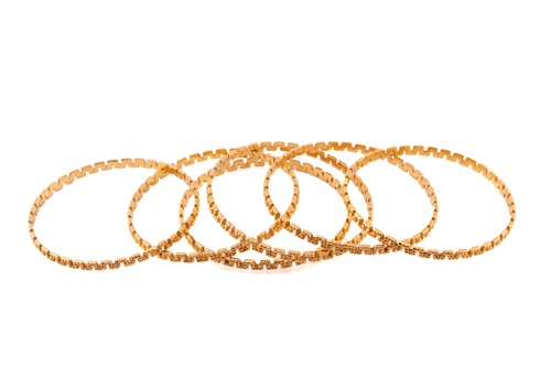 Lot 60 - A suite of six meander bangles, with a diamond...