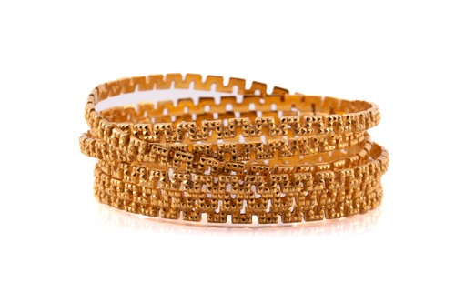 Lot 60 - A suite of six meander bangles, with a diamond...