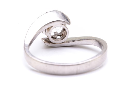 Lot 76 - A diamond solitaire bypass ring in platinum,...