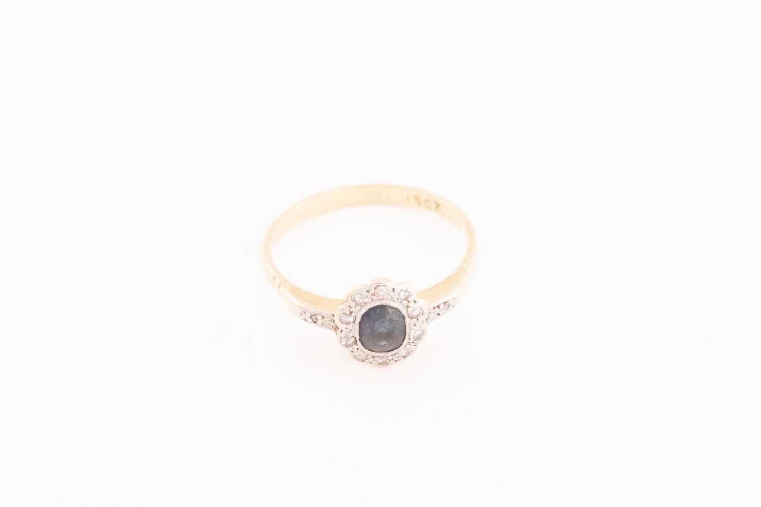 Lot 143 - A sapphire and diamond halo ring, comprises a...