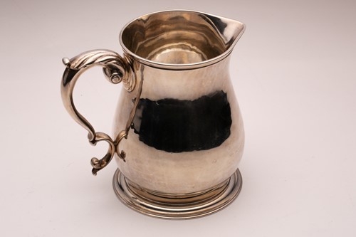 Lot 357 - A silver jug; baluster form with leaf-capped...