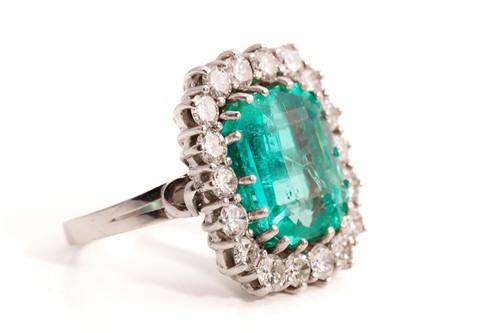 Lot 21 - An emerald and diamond entourage ring,...