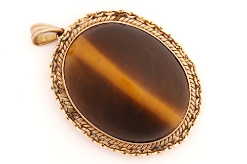 Lot 116 - A tiger's eye pendant, comprises an oval tiger'...