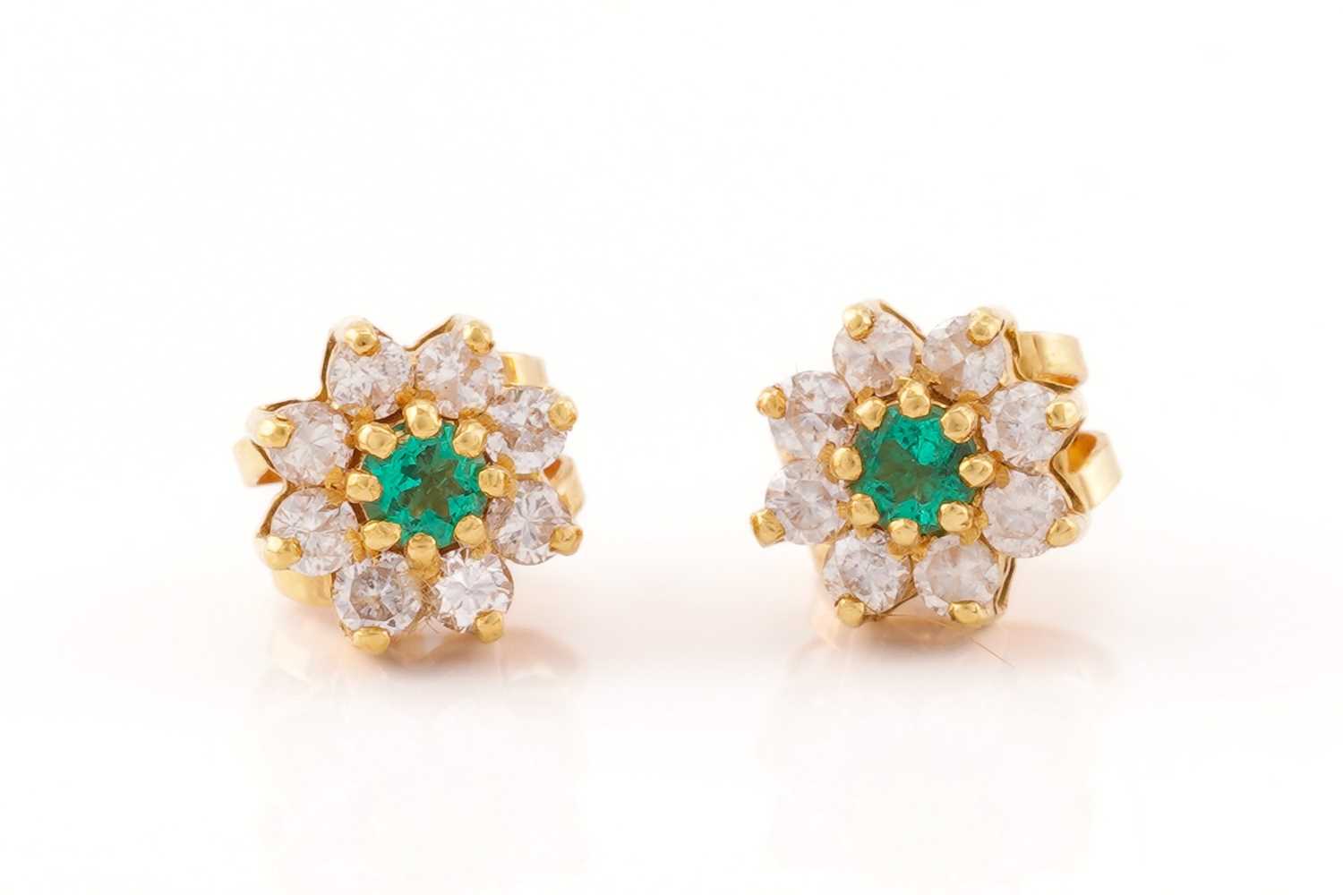Lot 128 - A pair of emerald and diamond flowerhead...