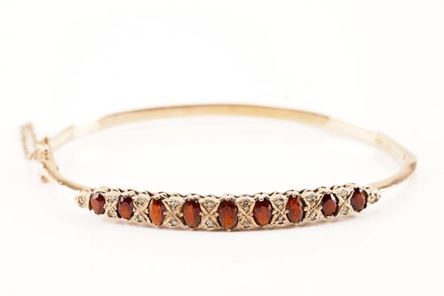 Lot 257 - A garnet and diamond hinged bangle in 9ct...