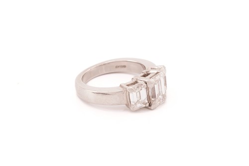 Lot 190 - An emerald-cut diamond trilogy ring in...