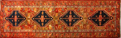 Lot 303 - An old red ground Karabakh runner with four...