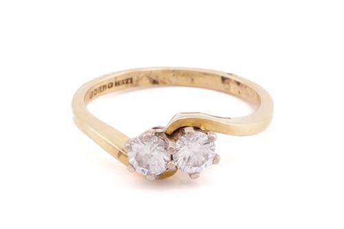 Lot 319 - A two stone diamond crossover ring; the round...