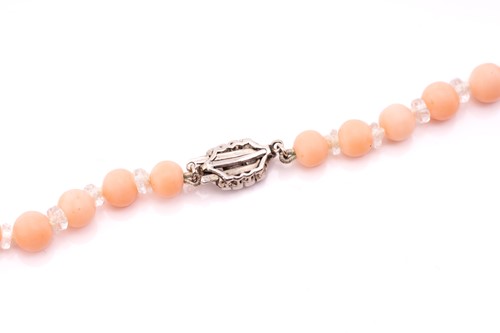 Lot 67 - A pink coral bead necklace with a diamond-set...