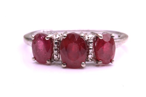 Lot 345 - A ruby and white metal three-stone ring, four...