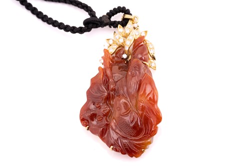 Lot 206 - A carved red jadeite and diamond pendant on a...