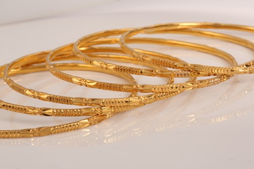 Lot 141 - A suite of six yellow metal bangles, in...