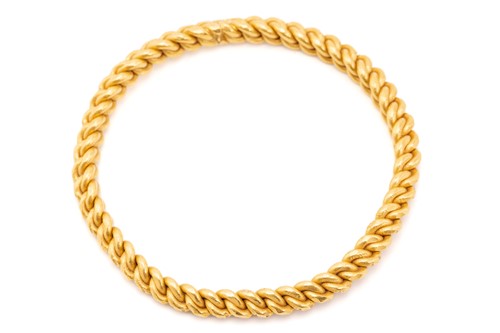Lot 140 - A high-carat gold closed bangle, of braided...