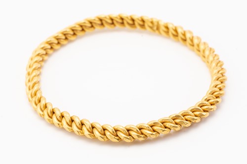 Lot 140 - A high-carat gold closed bangle, of braided...