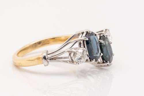 Lot 125 - A two stone sapphire and diamond ring; the...