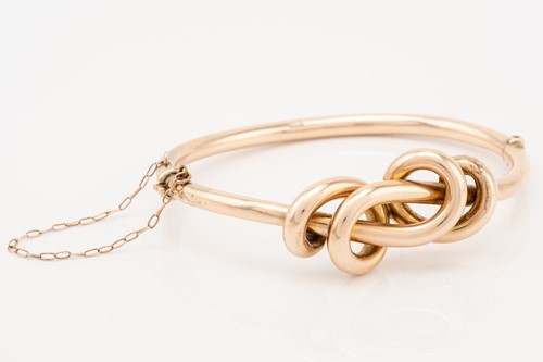Lot 221 - A rose gold knot bangle; the hinged hollow...