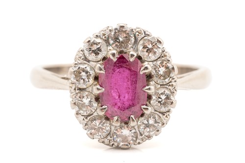 Lot 114 - A ruby and diamond halo ring, displaying an...