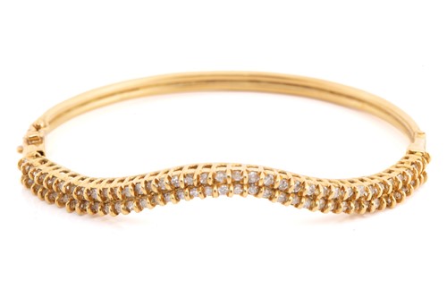 Lot 226 - A hinged bangle set with diamonds, the...