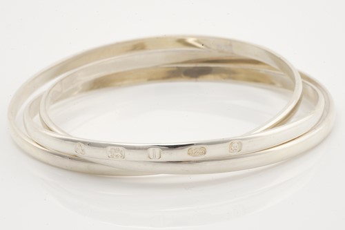 Lot 524 - A group of eleven silver trilogy bangles,...