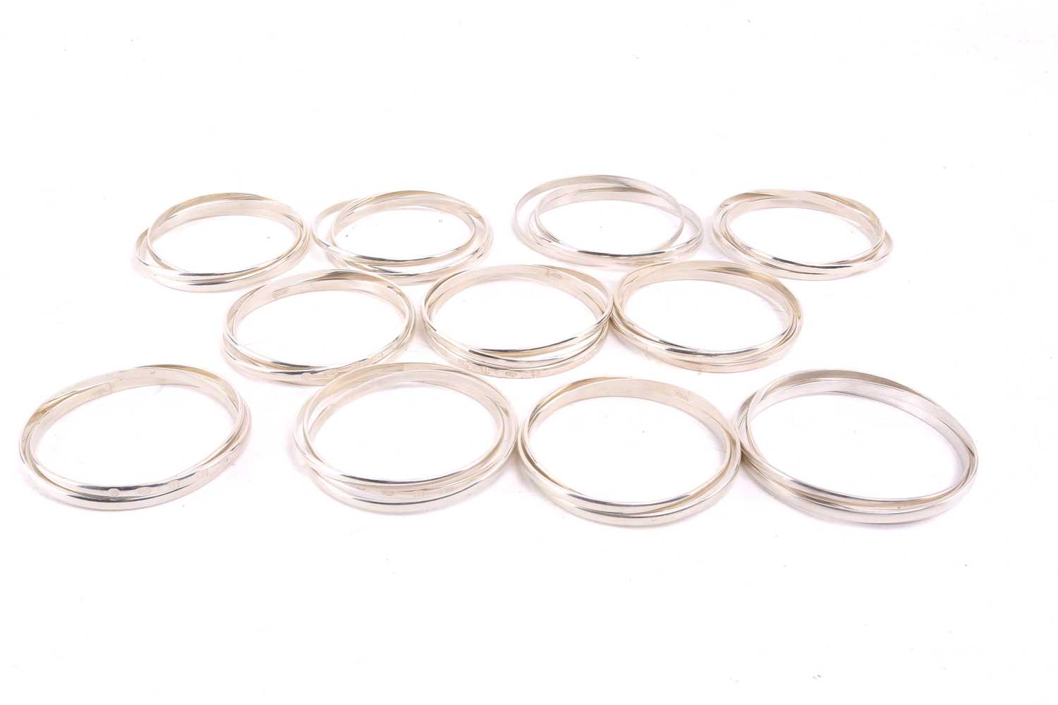Lot 524 - A group of eleven silver trilogy bangles,...