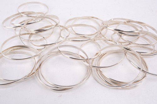 Lot 524 - A group of eleven silver trilogy bangles,...