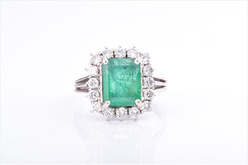 Lot 548 - An 18ct white gold, diamond, and emerald ring...