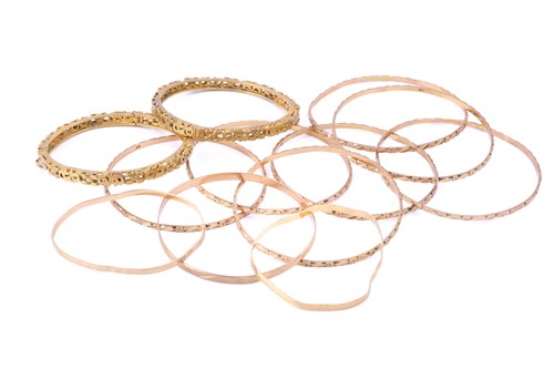 Lot 275 - A collection of yellow metal bangles;...
