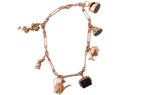 Lot 62 - A 9ct rose gold watch chain with charms,...