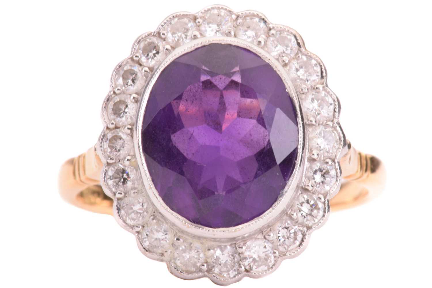 Lot 50 - An amethyst and diamond halo ring, featuring...