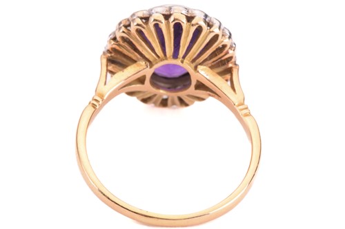 Lot 50 - An amethyst and diamond halo ring, featuring...