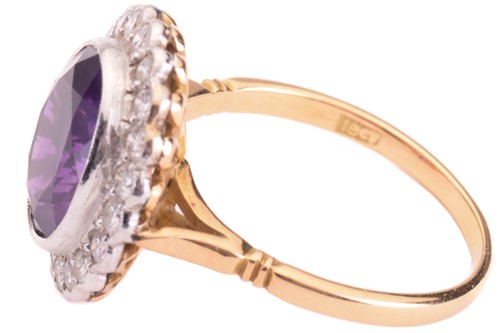 Lot 50 - An amethyst and diamond halo ring, featuring...