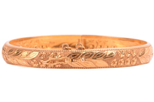 Lot 77 - A floral hinged bangle, with engraved foliate...