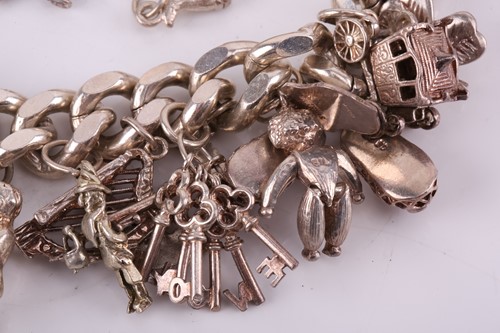 Lot 13 - A silver charm bracelet, the silver curb chain...