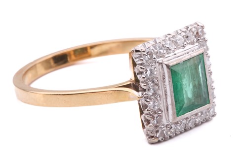 Lot 11 - An emerald and diamond halo ring, featuring a...