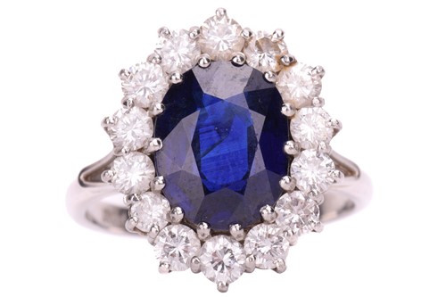 Lot 254 - A sapphire and diamond halo ring, featuring an...