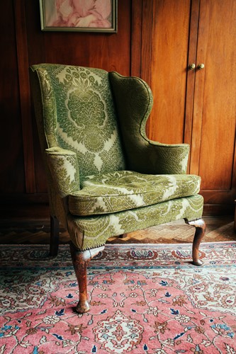 Lot 125 - A George II green-upholstered wing armchair,...