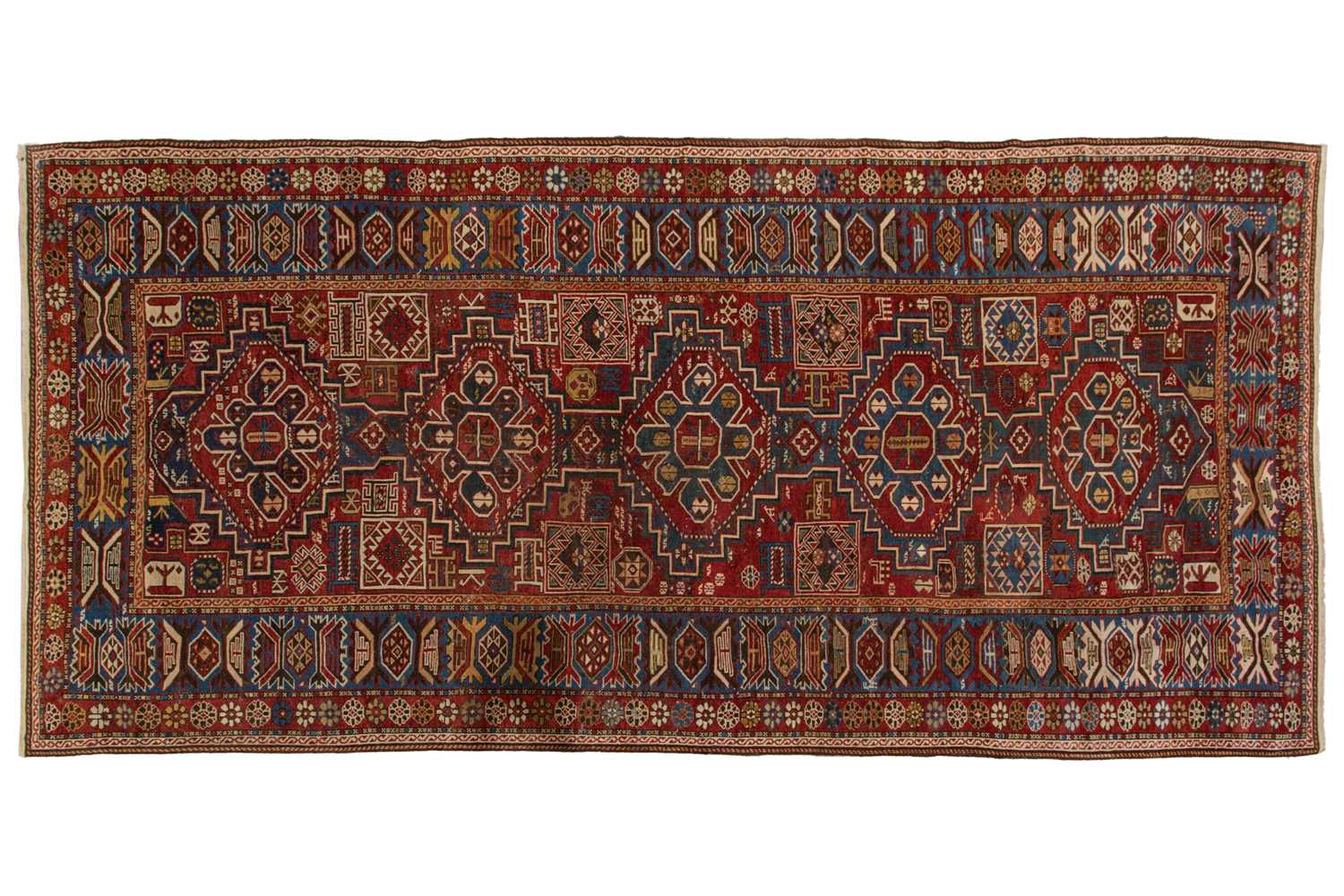 Lot 180 - An antique red ground Shirvan carpet with five...