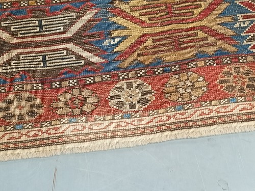 Lot 180 - An antique red ground Shirvan carpet with five...
