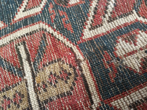 Lot 180 - An antique red ground Shirvan carpet with five...