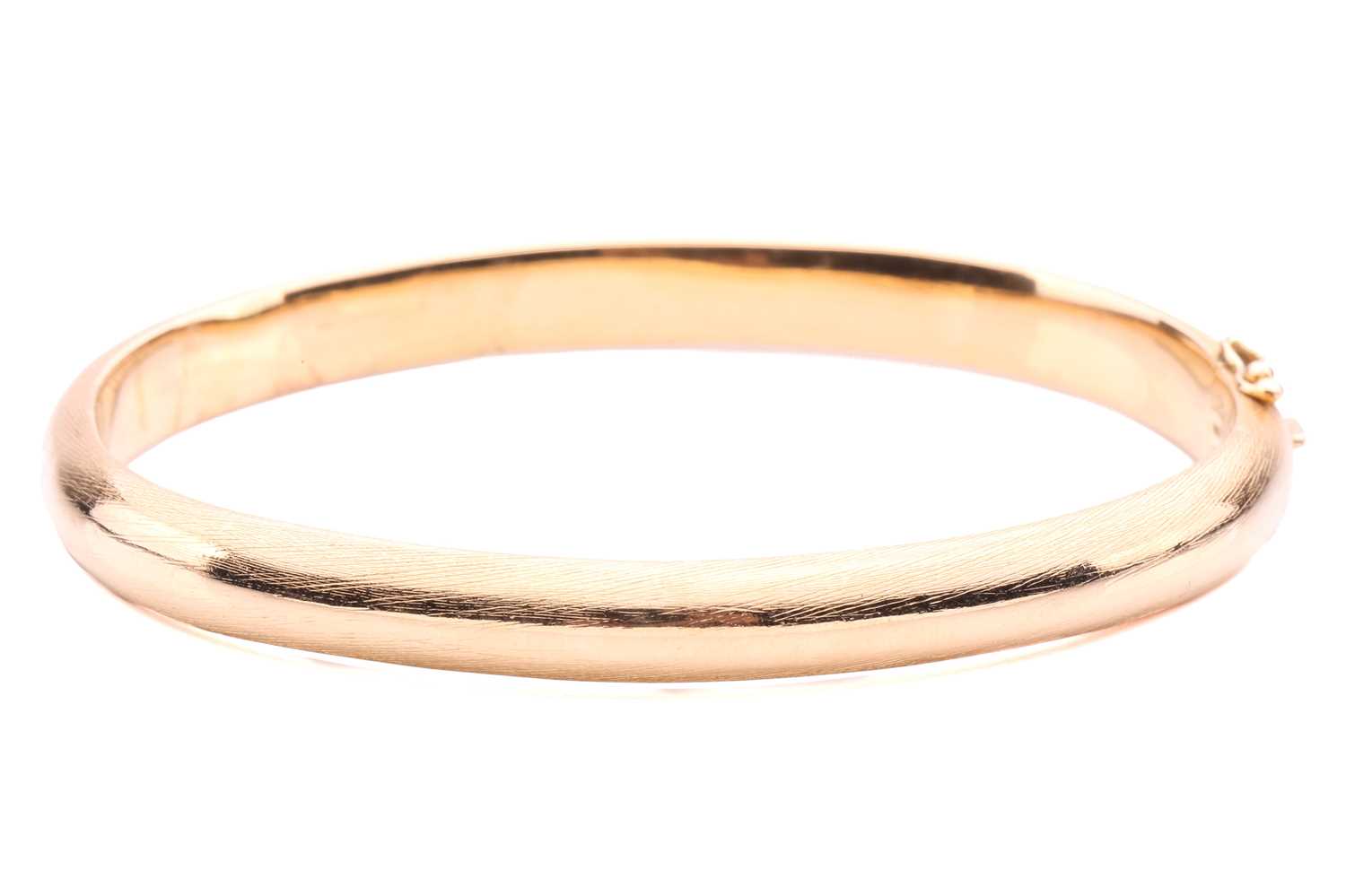 Lot 145 - A yellow metal bangle; brushed finish, with a...